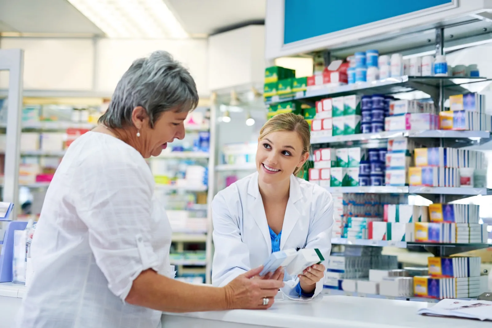 A pharmacist helping a customer with a medication question at the counter