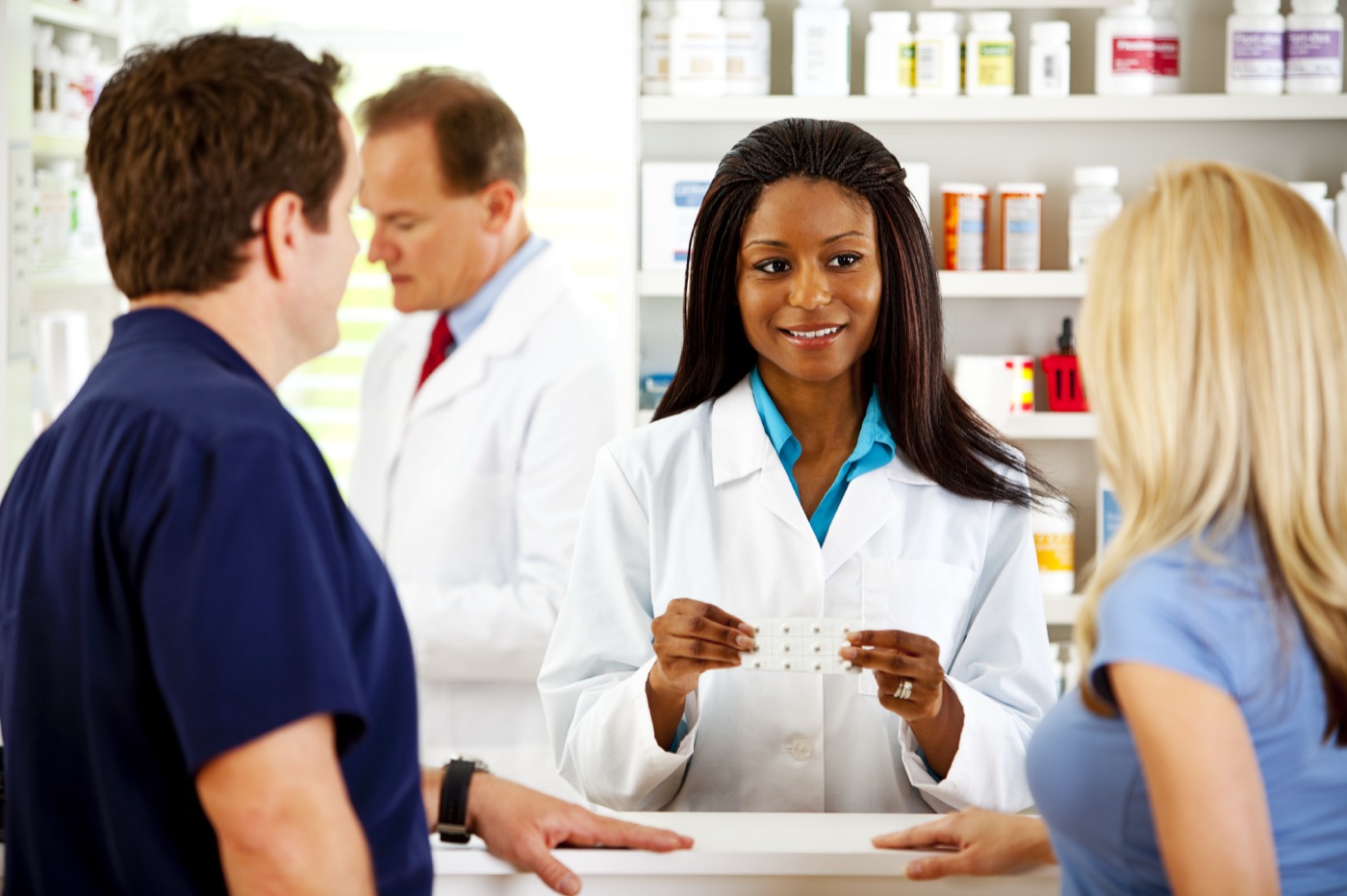 A pharmacist explaining a medication to customers at the counter