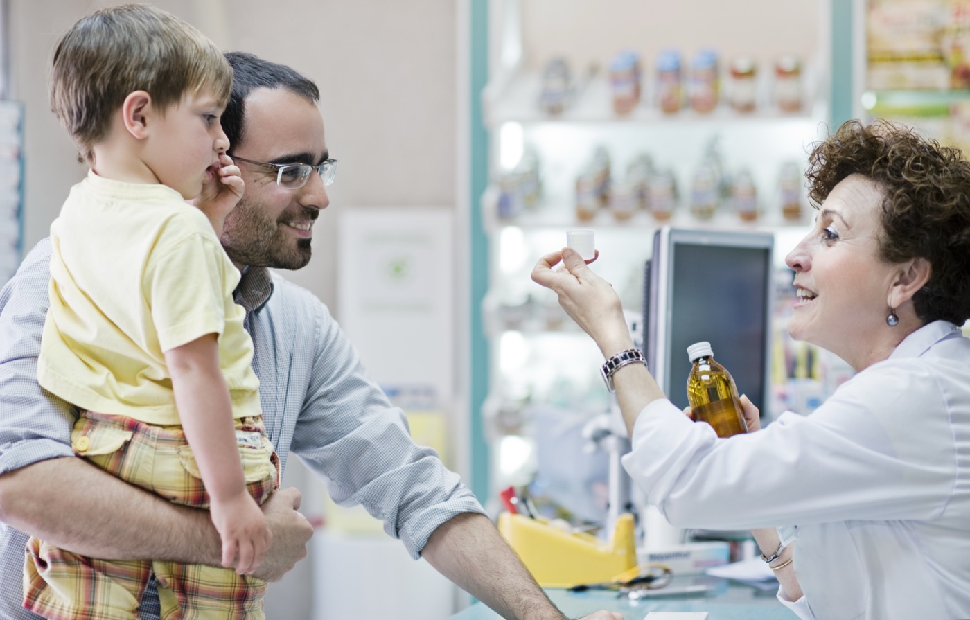 A pharmacist helping a parent and child at the pharmacy counter