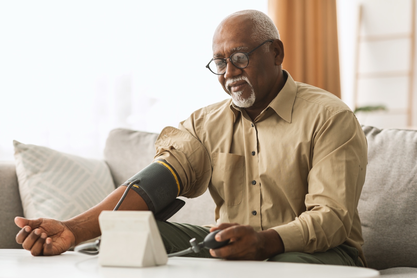 A patient checking his blood pressure at home with a monitor
