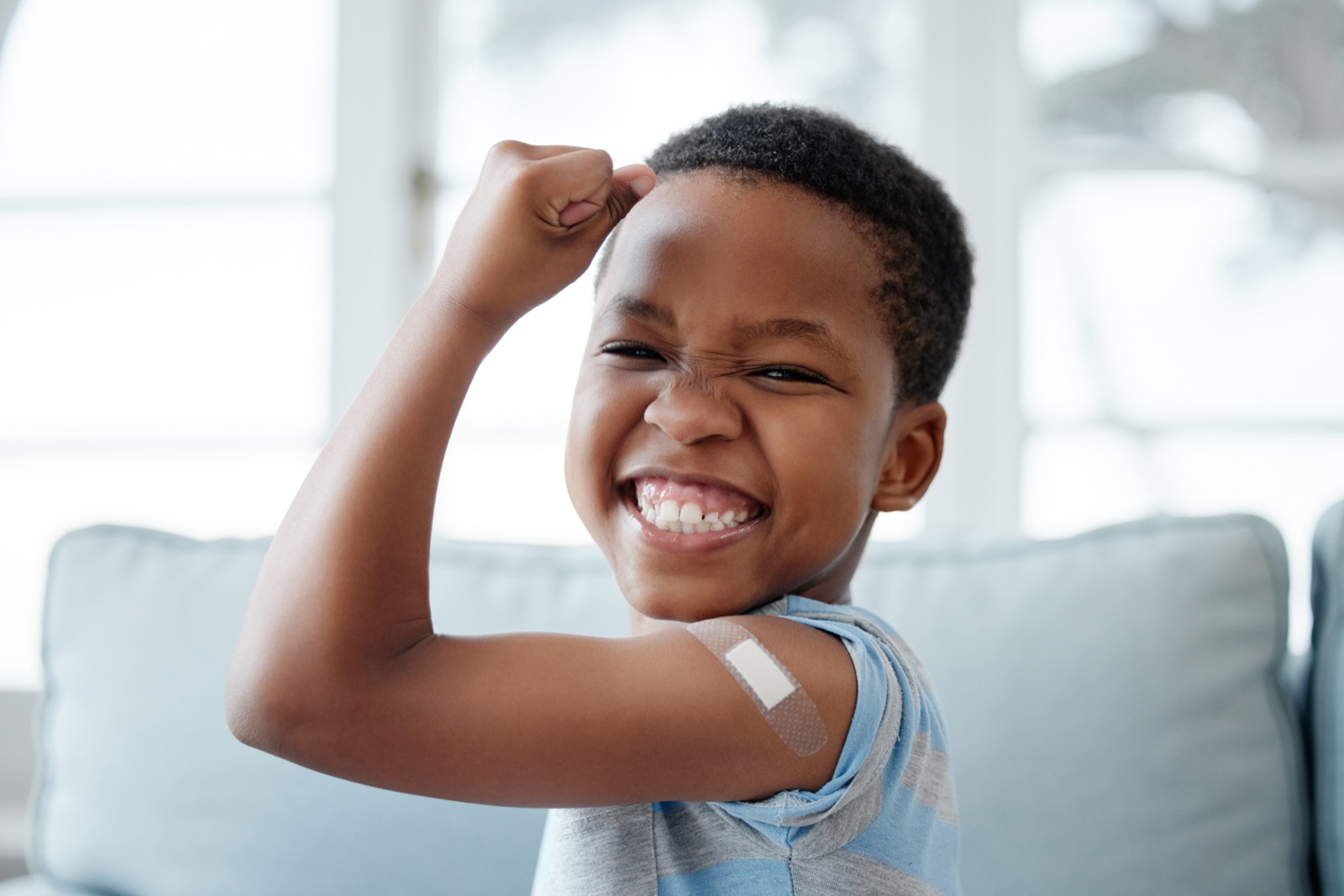 A child smiling and flexing his arm after a vaccination